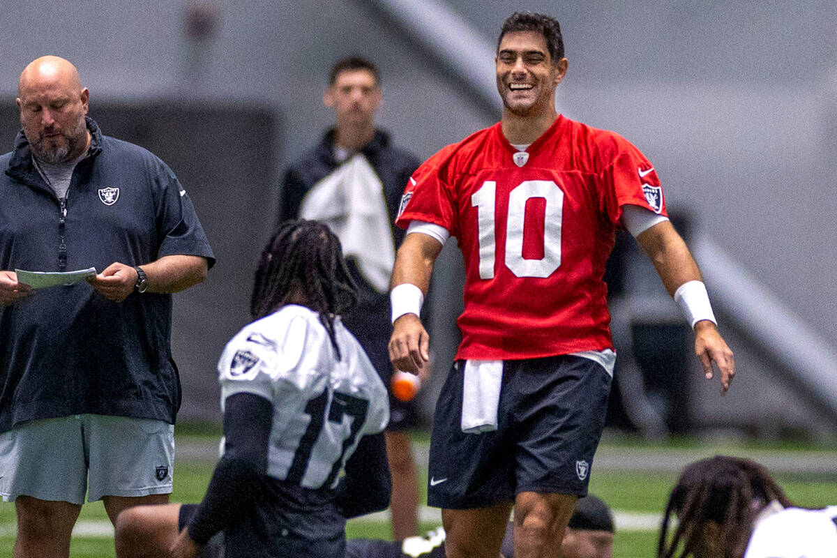 Raiders quarterback Jimmy Garoppolo (10) talks with wide receiver Davante Adams (17) during tra ...