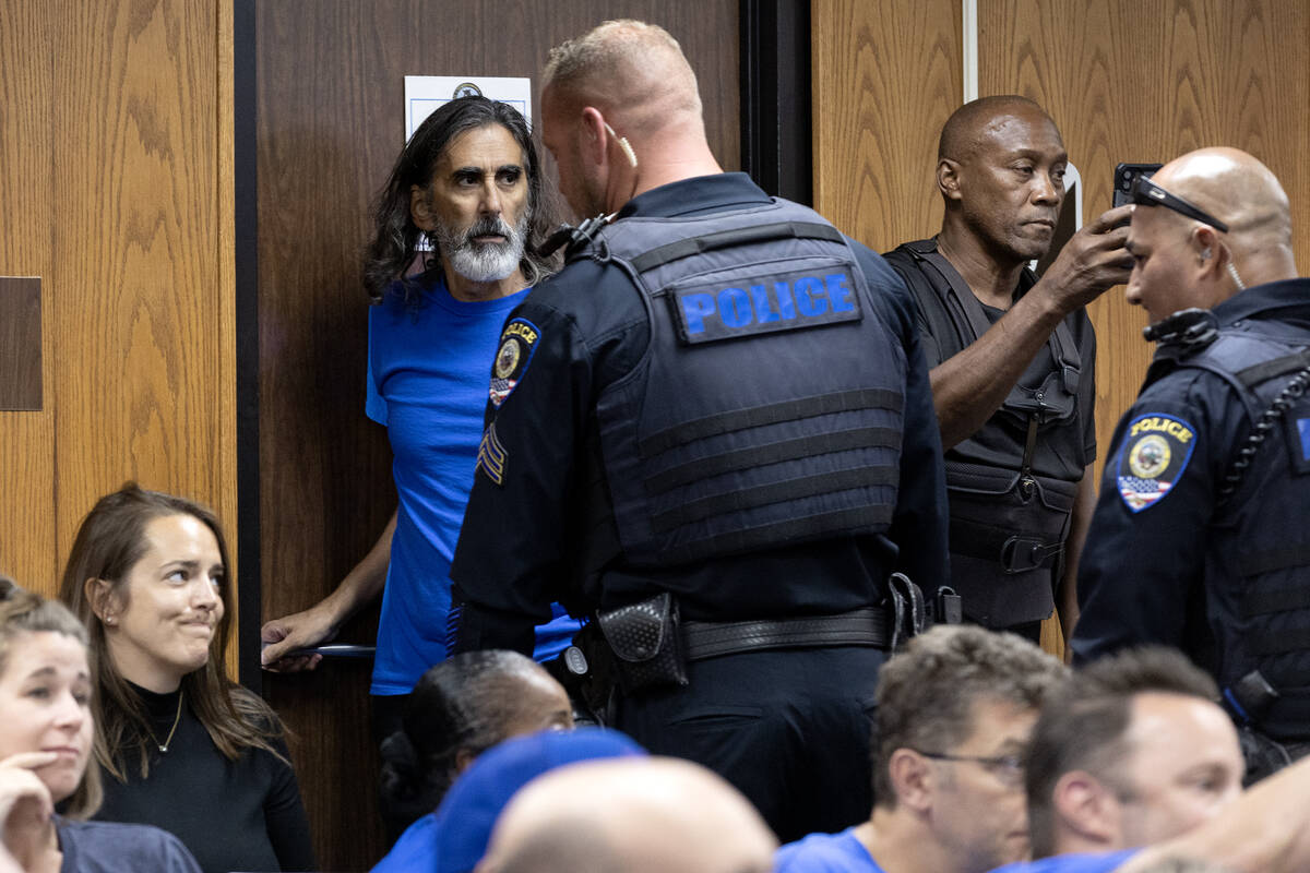 A police officer escorts Aramis Bacallao, a teacher at Ernest A. Becker Middle School, from a s ...