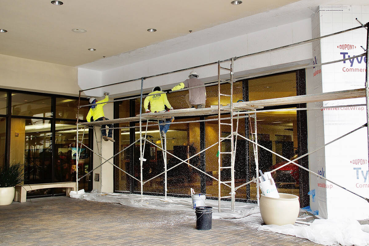 Workers install an exterior insulation finishing system at the front entrance of Lexus of Las V ...