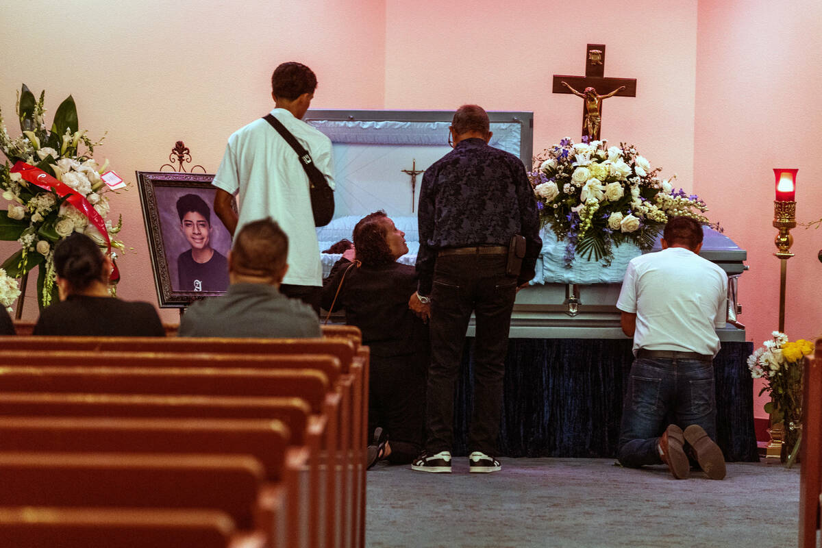 Rudolfo Naranjo, right, prays beside family members at the casket of his son Angel before funer ...