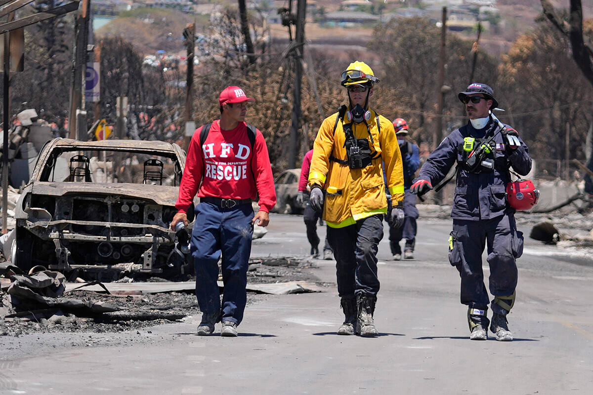 Members of a search-and-rescue team walk along a street, Saturday, Aug. 12, 2023, in Lahaina, H ...