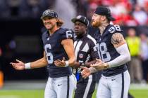 Raiders punter AJ Cole (6) and defensive end Maxx Crosby (98) run off the field after the coin ...