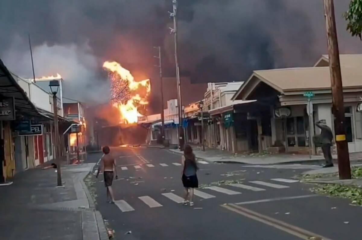 People watch as smoke and flames fill the air from raging wildfires on Front Street in downtown ...