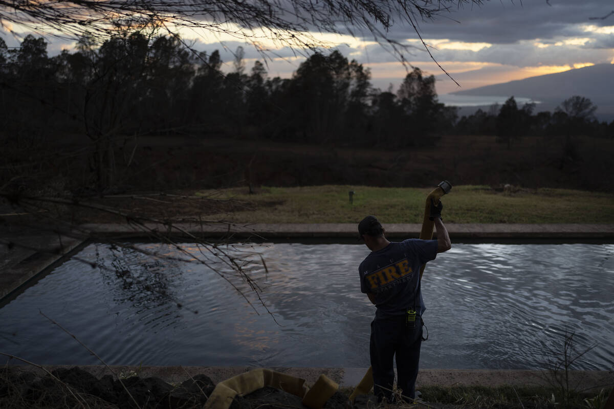 A firefighter pulls a water hose out of a pool after filling it with water for firefighting hel ...