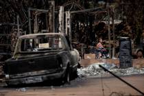 A resident reacts as she walks through the ruins of a a house destroyed by the Lahaina Fire, in ...