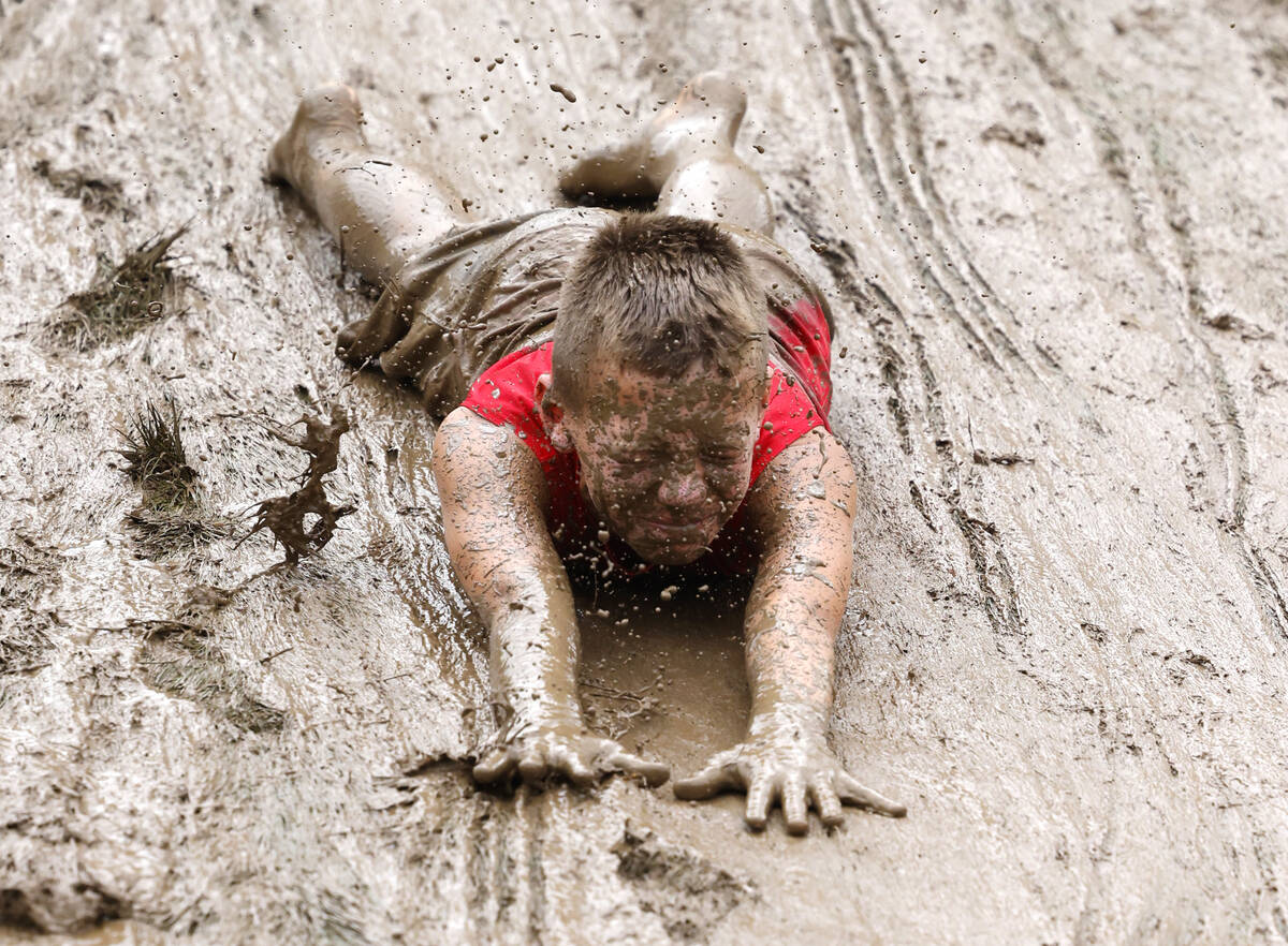 Landon Frilling, 10, of Ohio, slides on the muddy hillside overlooking Howard J. Lamade Stadium ...