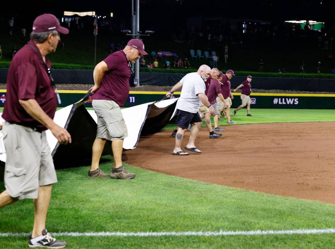 Members of the grounds crew cover the field with a tarp during a rain delay during the Little L ...