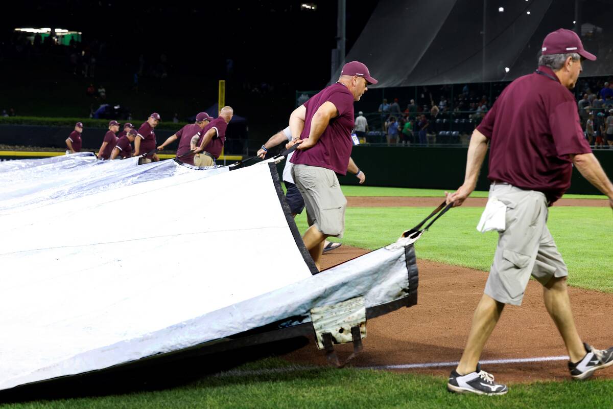 Members of the grounds crew cover the field with a tarp during a rain delay during the Little L ...