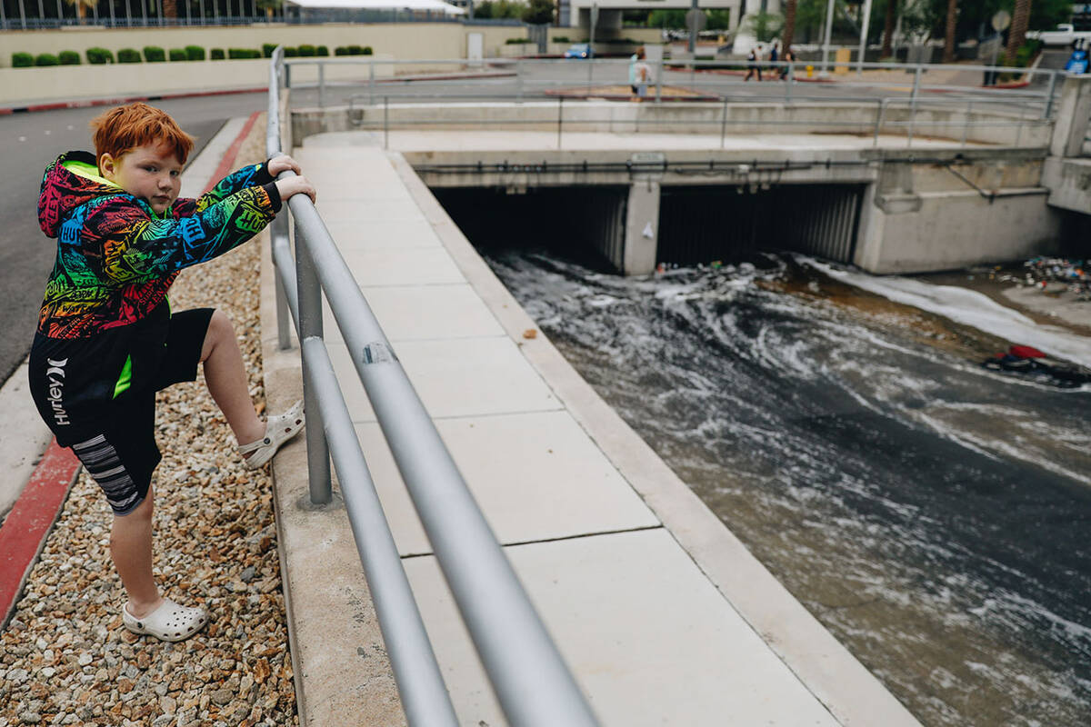 Jack Fargo, 7, watches as water flows out of The Linq parking garage into a flood channel on Su ...