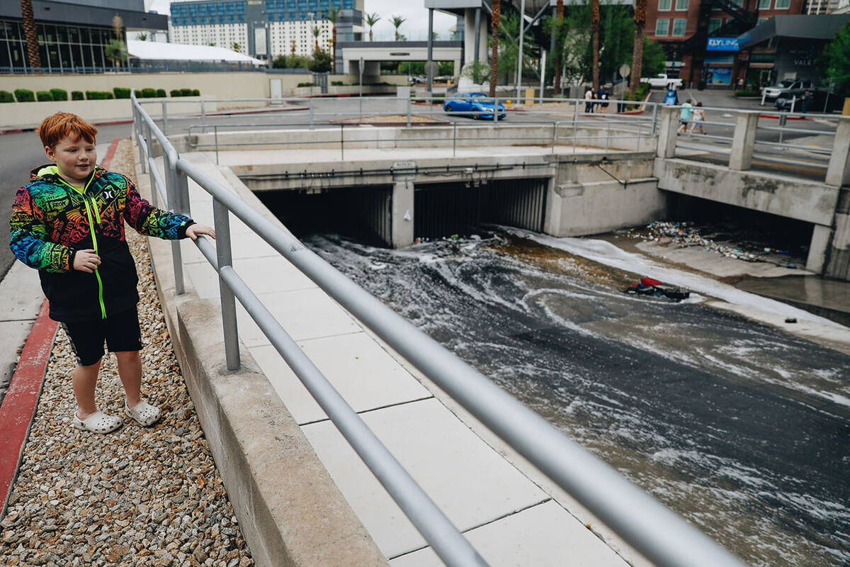 Jack Fargo, 7, watches as water flows out of The Linq parking garage into a flood channel on Su ...