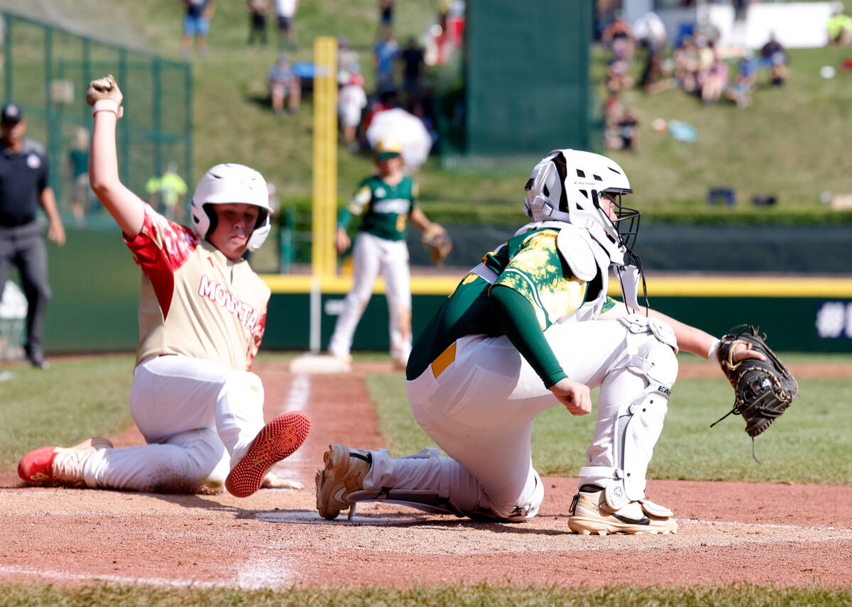 The Henderson All-Stars third baseman Logan Levasseur, left, slides and scores as Fargo, North ...