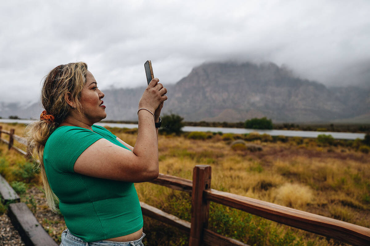 Janette Espejo takes a photograph of the fog and clouds from storms in the Red Rock National co ...