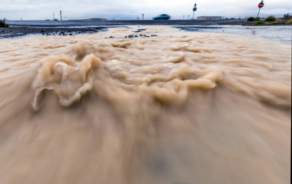 Flood waters move down the street onto Highway 160 as the remnants of tropical storm Hilary mov ...