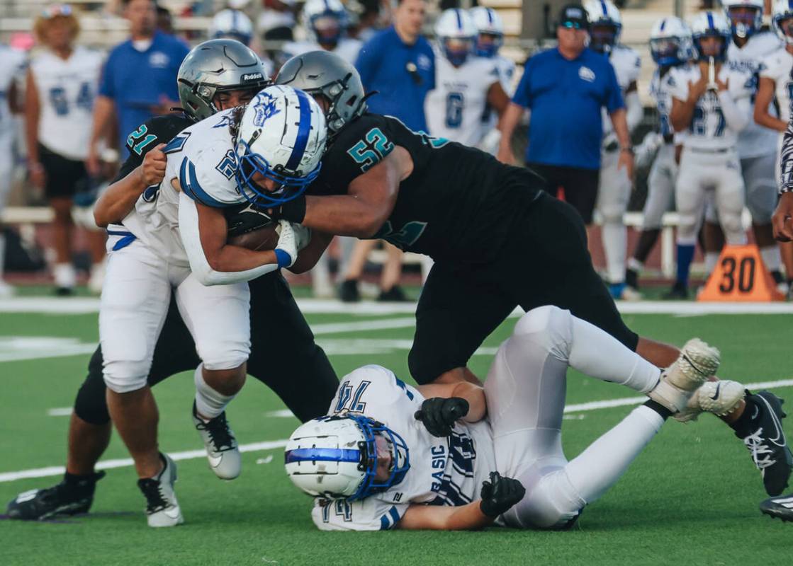 Basic running back Boston Wren (24) gets wrapped up by Silverado's Noah Mendez (21) and Jayland ...