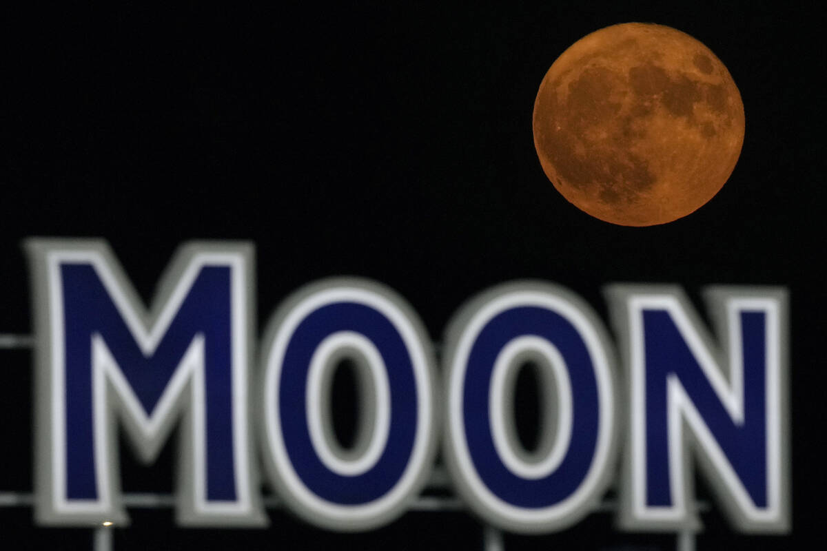 FILE - A supermoon rises beyond a beer sign at Kauffmann Stadium during a baseball game between ...