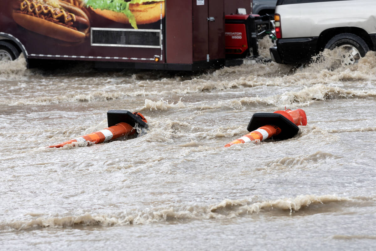 Cones are knocked over while a trailer drives through flash flooding at East Sahara Avenue and ...