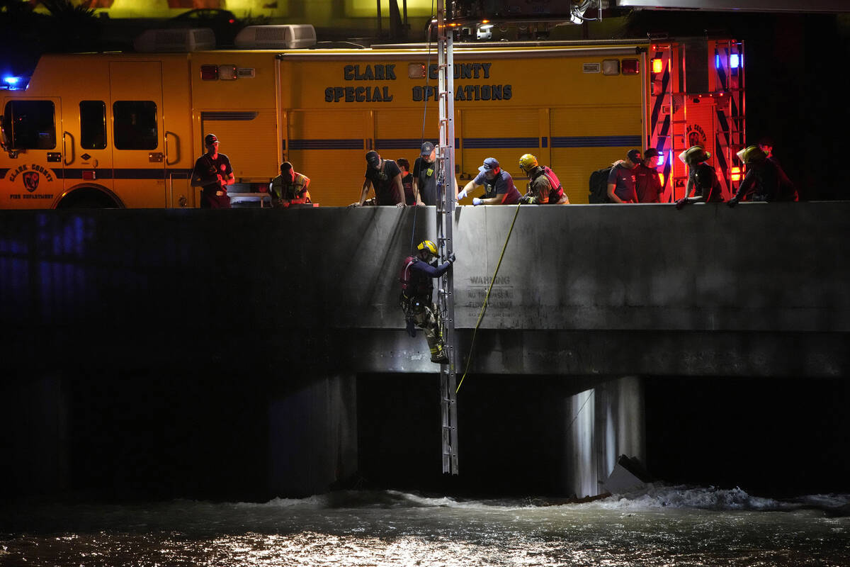 A Clark County Fire Department official climbs down a ladder to search for a man who was trappe ...