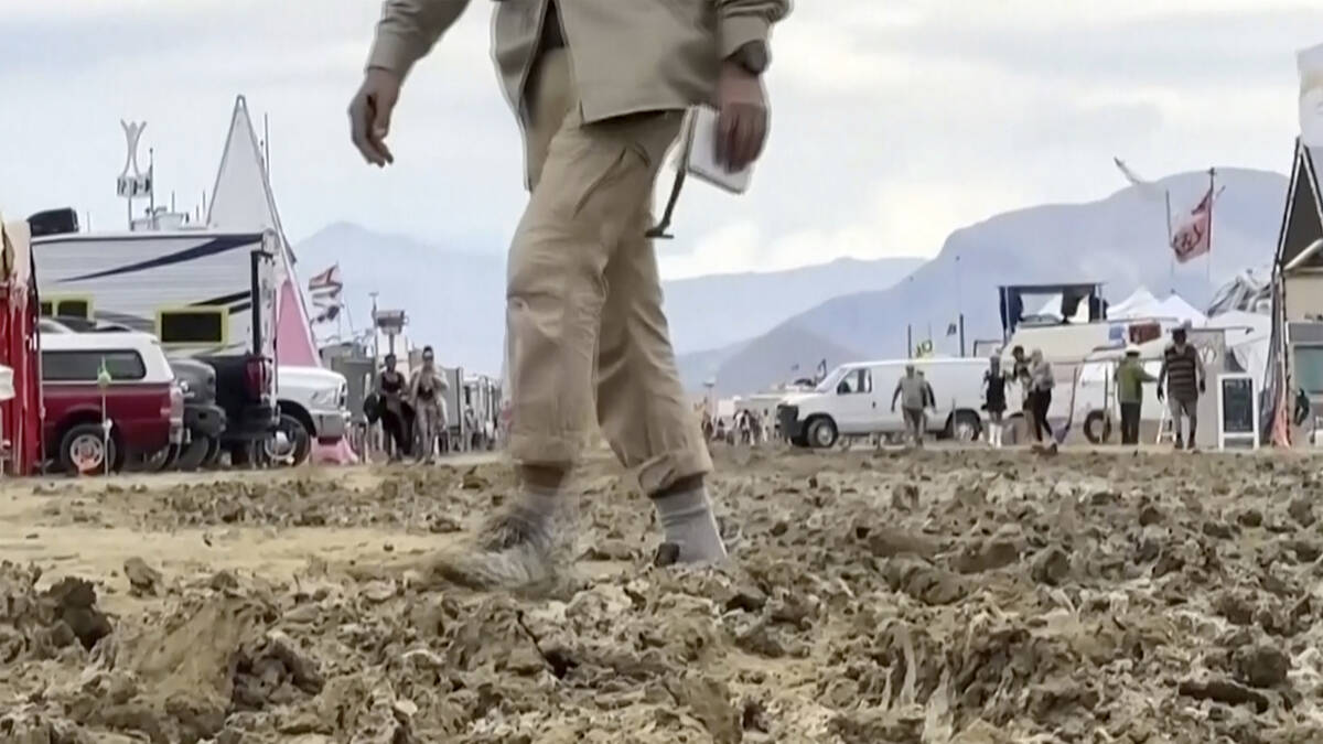 In this image from video provided by Rebecca Barger, a man walks through mud at the Burning Man ...