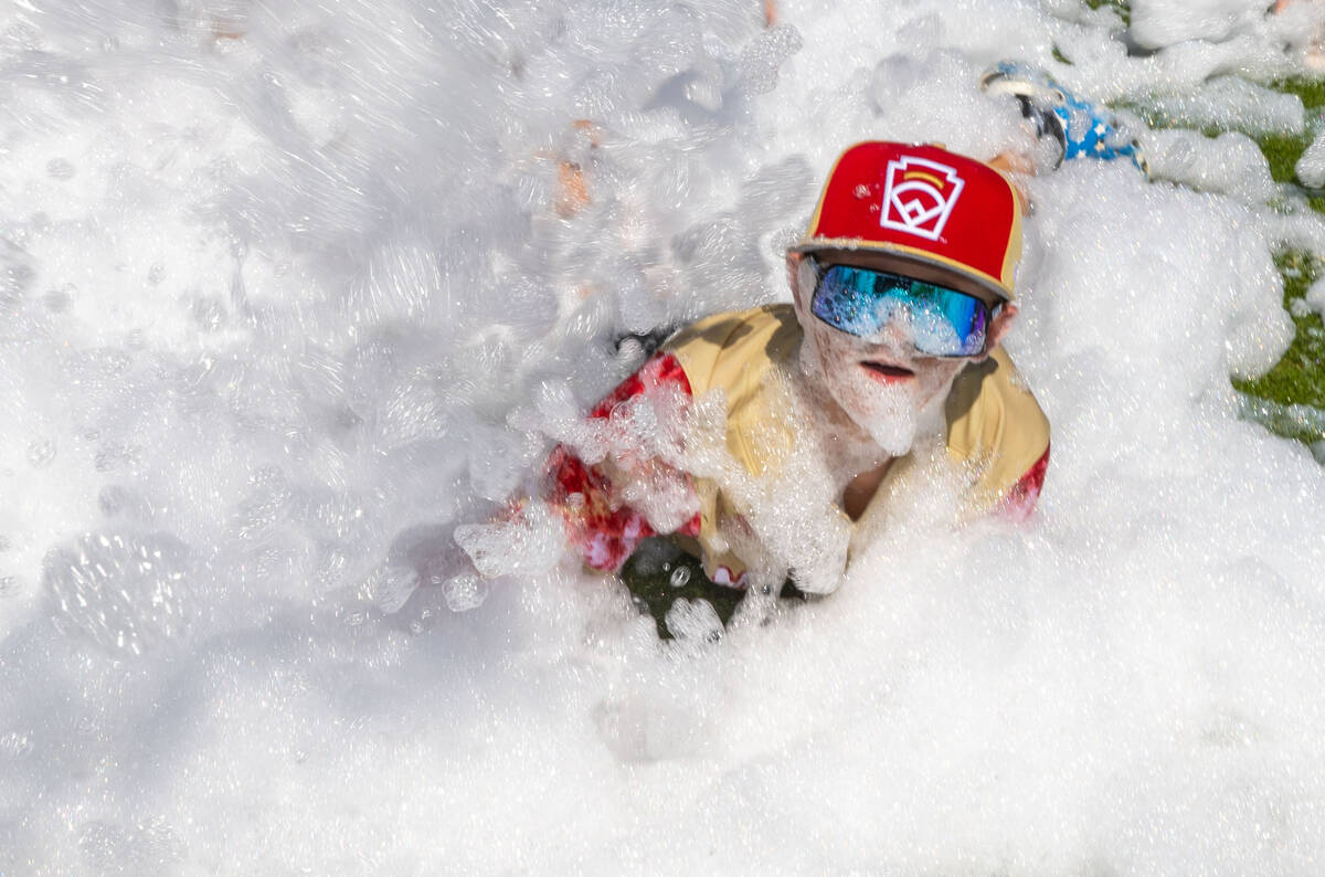 Henderson Little League team player Jaxon McMullin (17) is covered in bubbles pumped from a blo ...