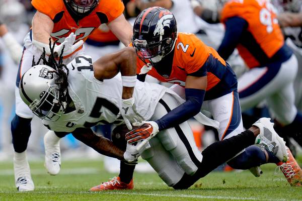 Las Vegas Raiders wide receiver Davante Adams (17) is hit by Denver Broncos cornerback Pat Surt ...