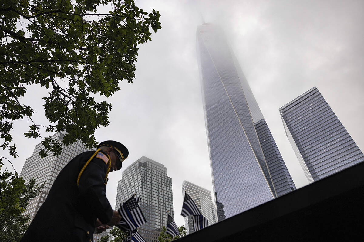 Sam Pulia places flags before the commemoration ceremony of the Sept. 11, 2001, terror attacks, ...