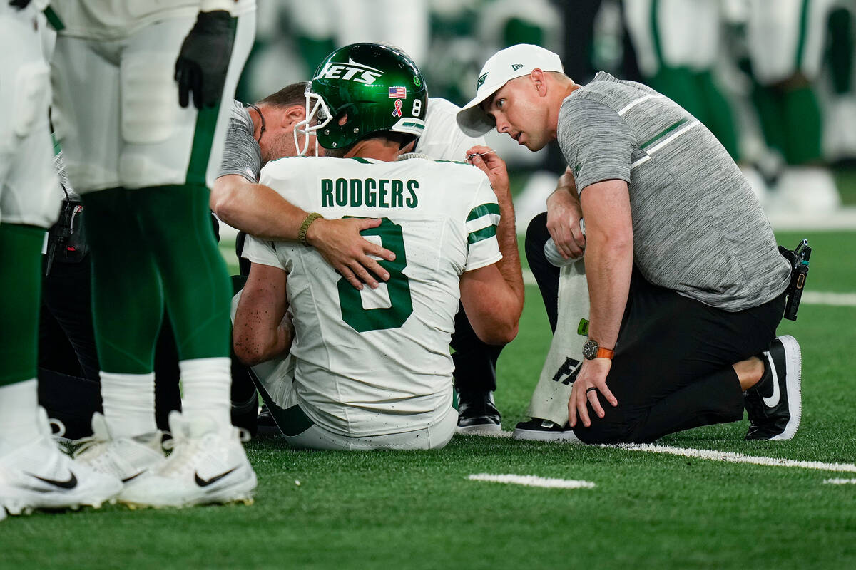 New York Jets quarterback Aaron Rodgers (8) is tended to on the field during the first quarter ...