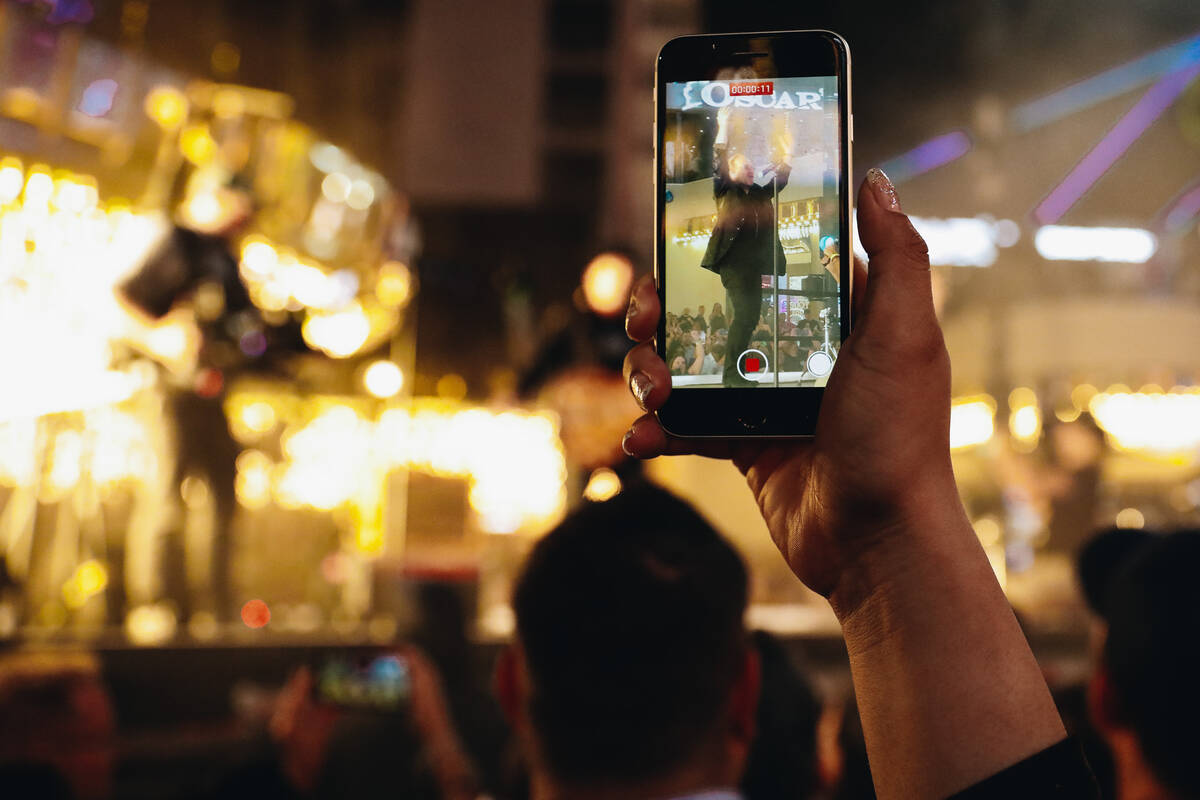 A fan records U2 during a surprise concert in front of the Plaza hotel and casino on Sunday, Se ...