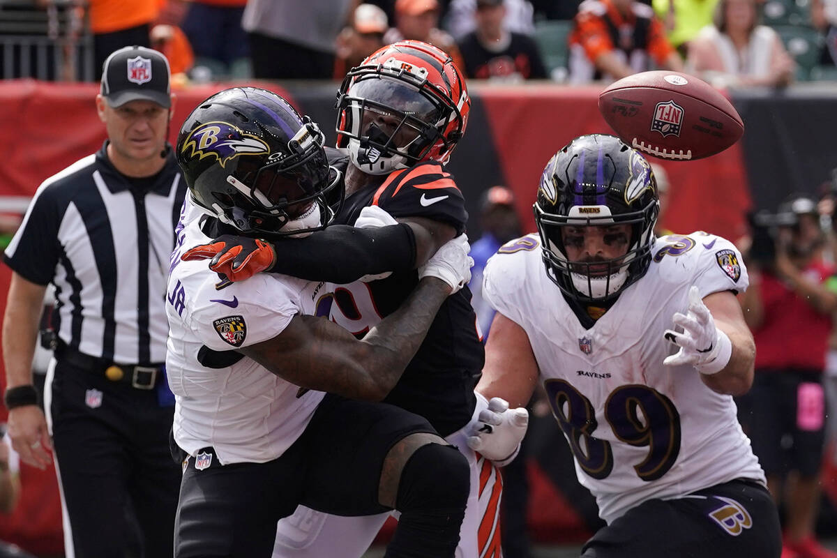 Cincinnati Bengals cornerback Cam Taylor-Britt, center, breaks up a pass intended for Baltimore ...