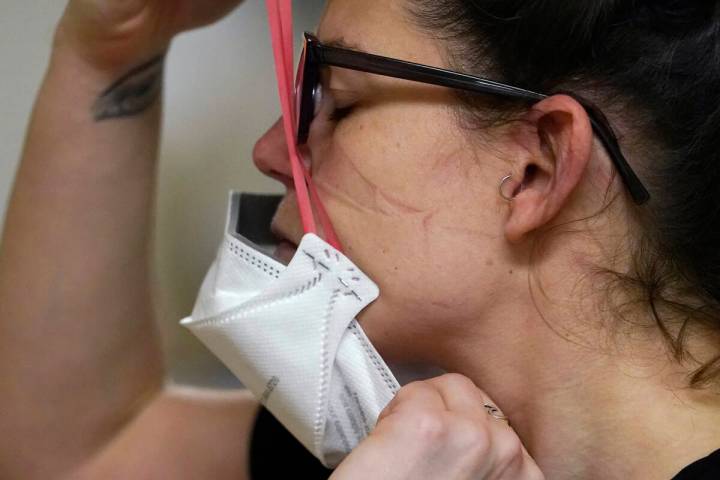 FILE - Registered nurse Jessalynn Dest pulls on a new N95 mask after leaving a COVID-19 patient ...