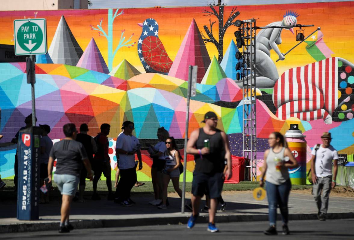 Attendees pass by a new mural during the first day of the Life is Beautiful festival in downtow ...