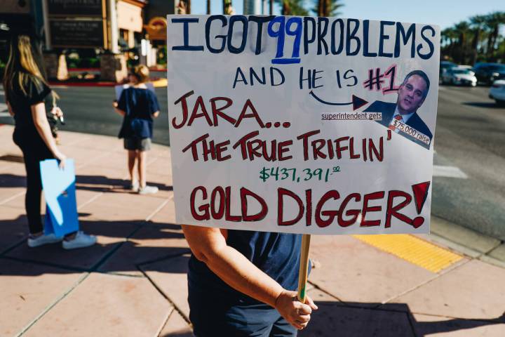 A protester, who did not want their face to be shown, holds up a sign directed at Dr. Jesus Sar ...