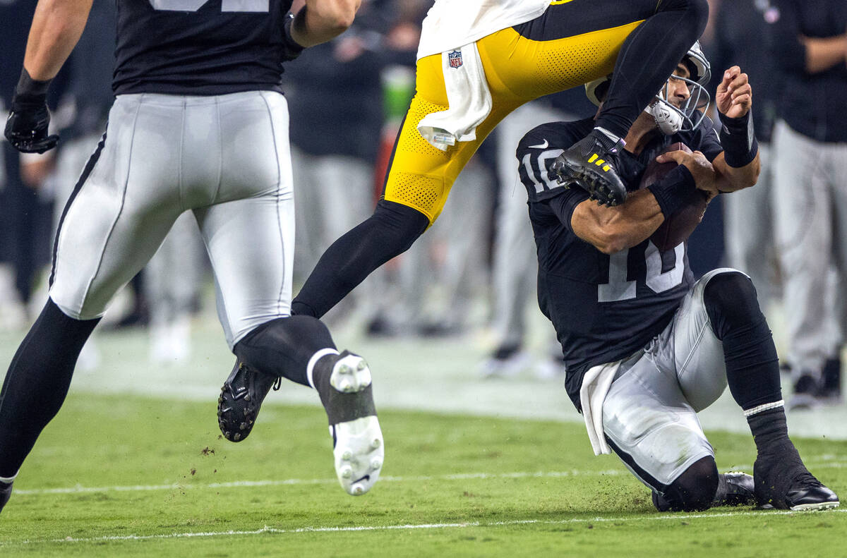 Raiders quarterback Jimmy Garoppolo (10) slides on a run but takes a knee to the helmet from Pi ...