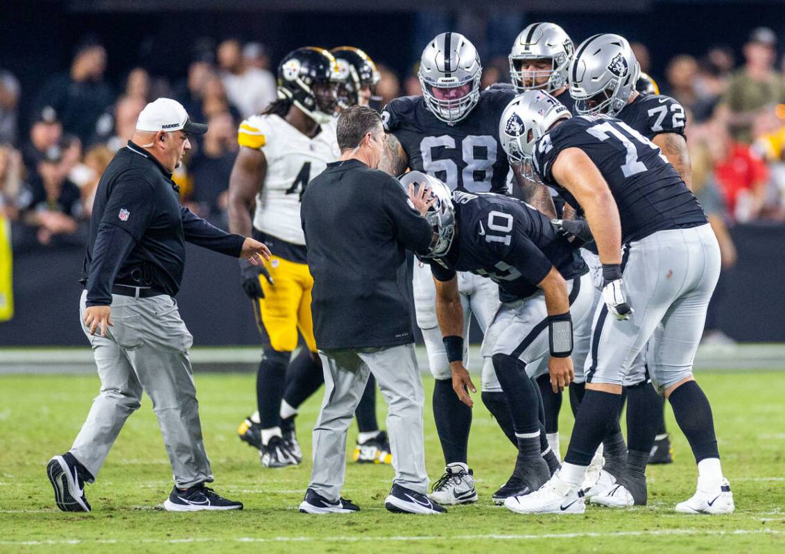 Raiders quarterback Jimmy Garoppolo (10) looked at by medical trainers after being bent back on ...