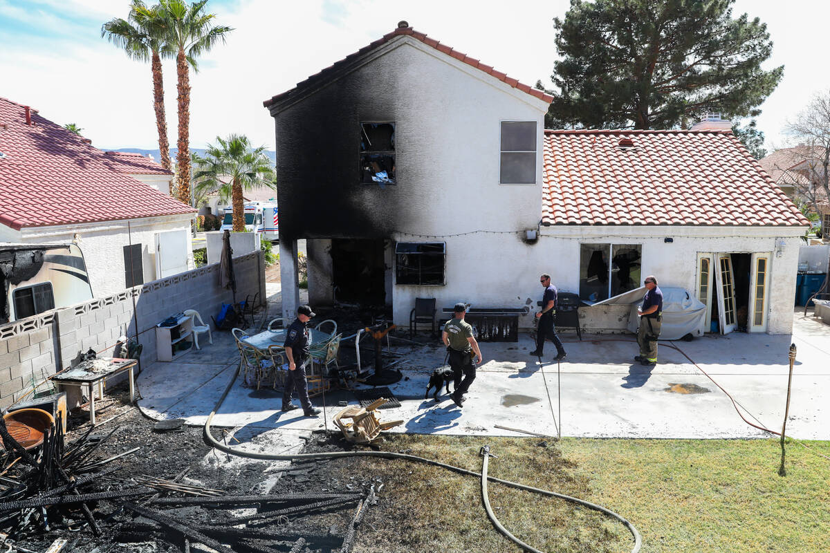 Henderson police and firefighters investigate the perimeter of a home demolished by a fire, whi ...