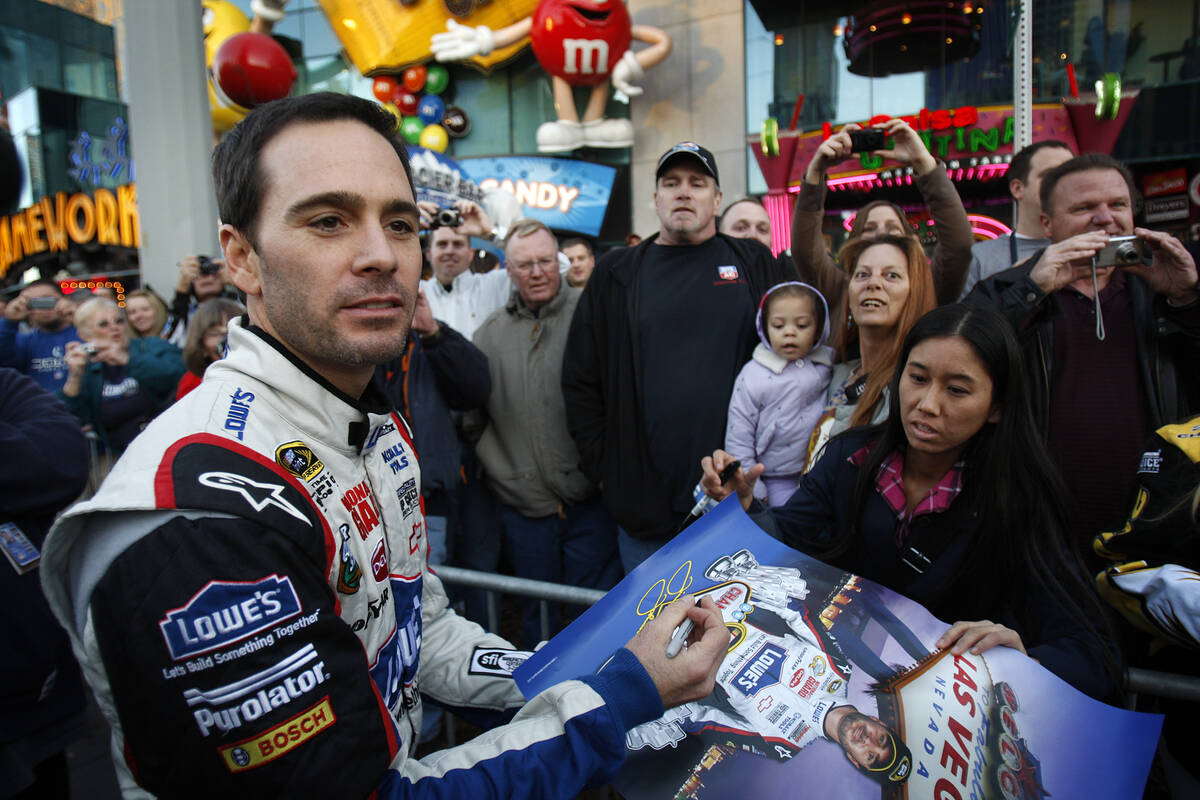 NASCAR driver Jimmie Johnson signs a poster for a fan in front of the MGM Grand hotel-casino du ...