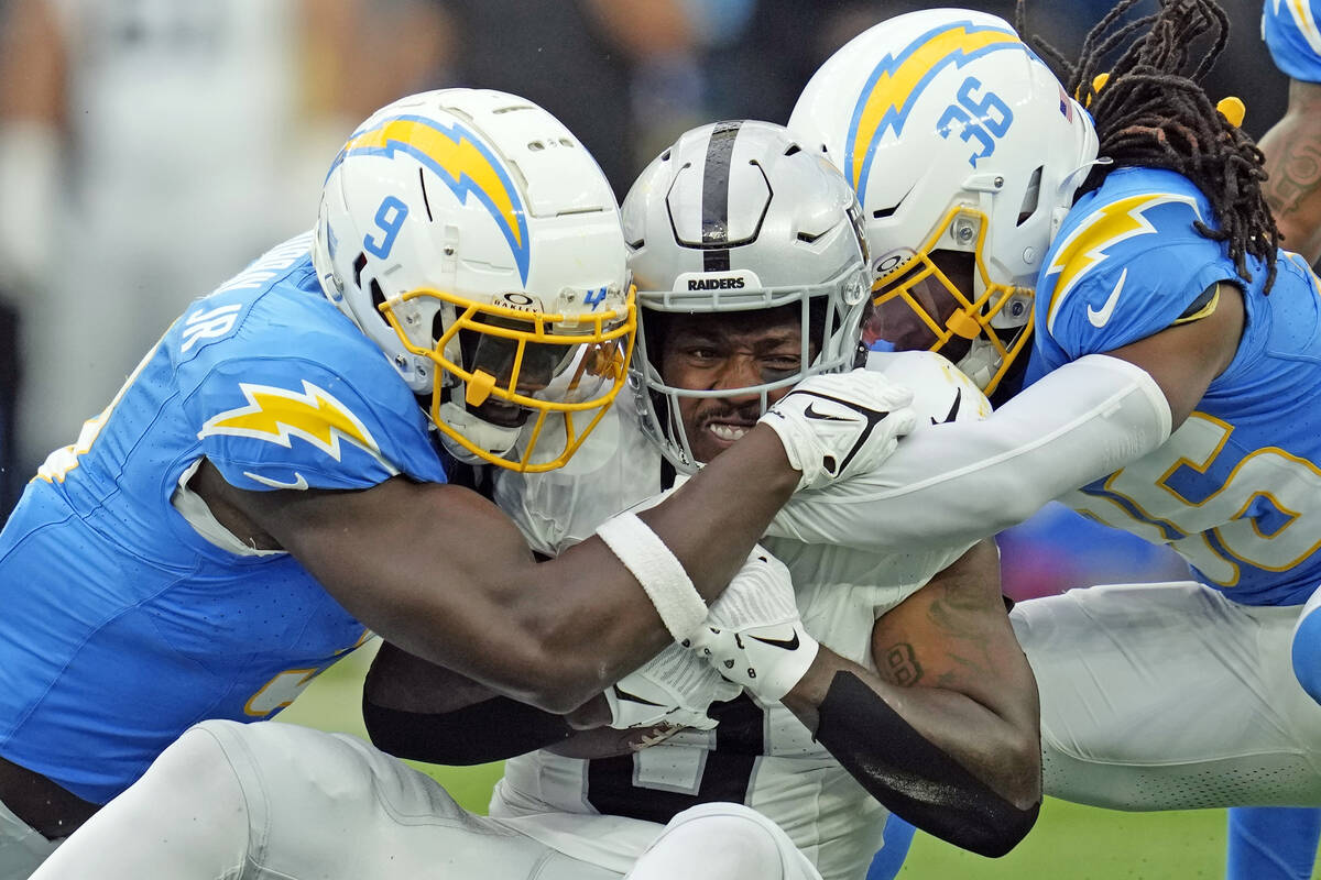 Las Vegas Raiders running back Josh Jacobs, center, is tackled by Los Angeles Chargers lineback ...