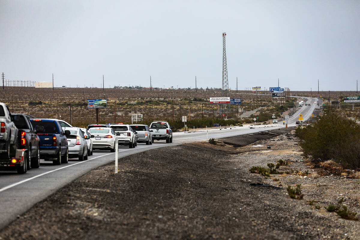 Cars wait to be guided by a pilot car along State Route 160 after a portion of the road was was ...