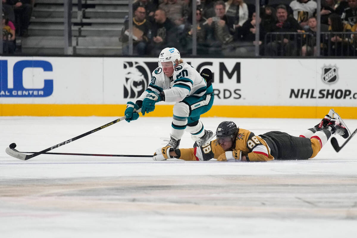 Vegas Golden Knights' Maxime Comtois, right, knocks the puck away from San Jose Sharks left win ...