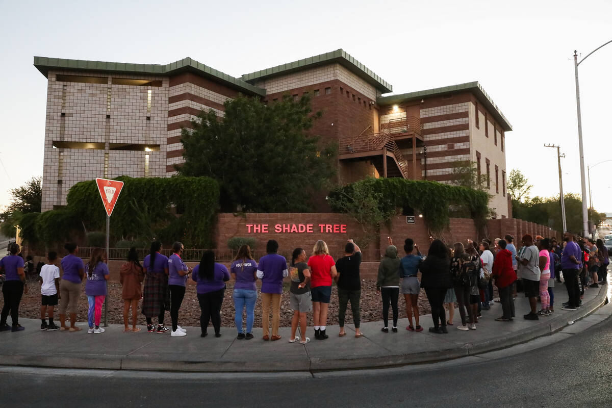 Survivors of domestic abuse gather in front of The Shade Tree with candles in hand during a vig ...