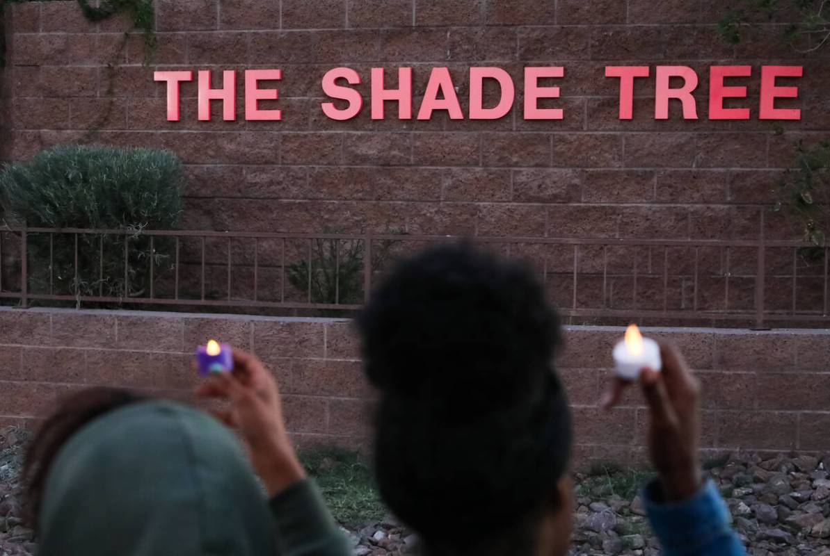 Survivors of domestic abuse gather in front of The Shade Tree with candles in hand during a vig ...