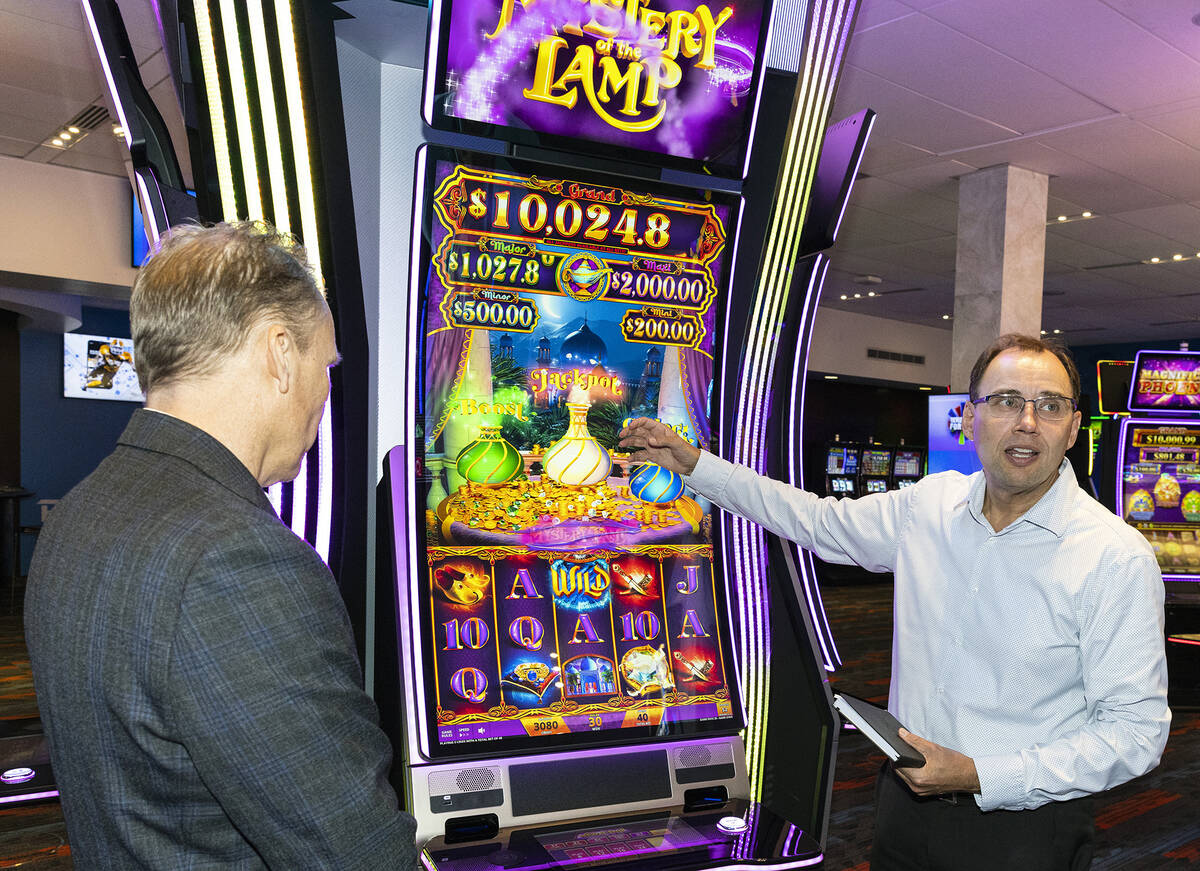 Nick Khin, right, a COO of Gaming for IGT, demonstrates how Mystery of the Lamp game is played ...