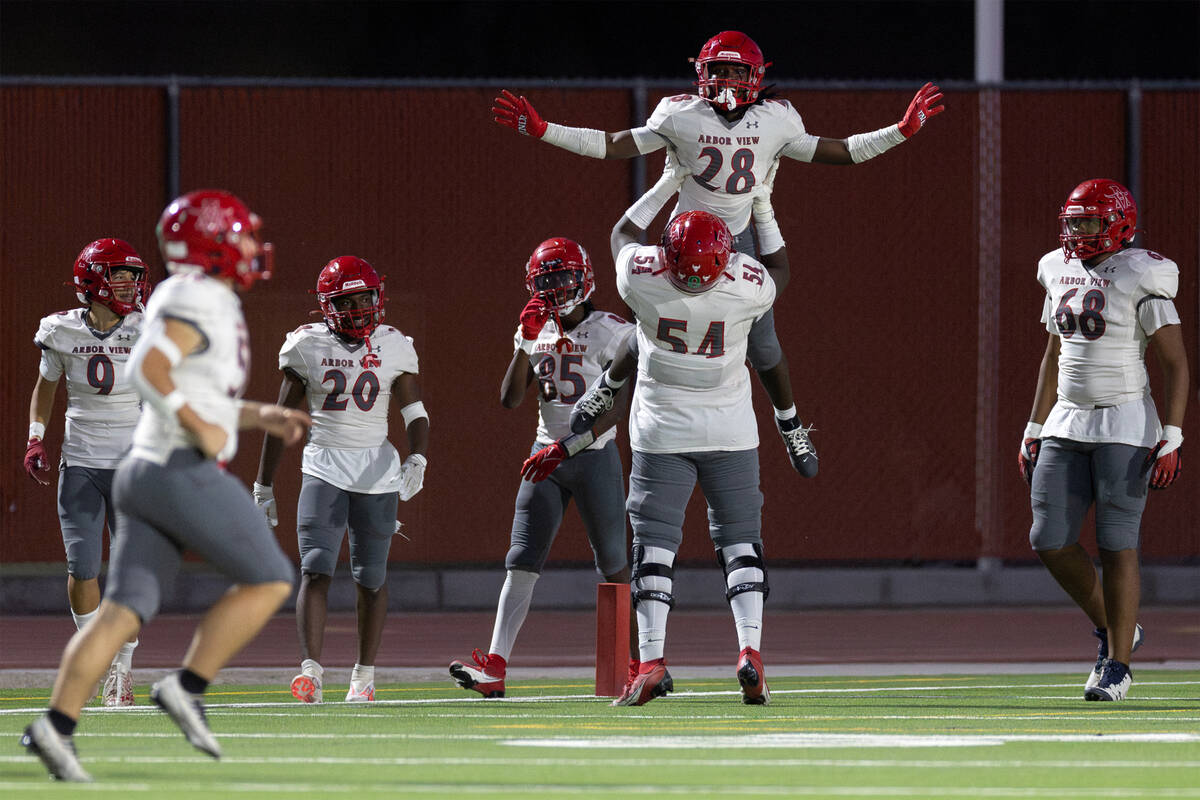 Arbor View guard Daniel Boyd (54) lifts running back Nylen Johnson (28) after Johnson scored a ...