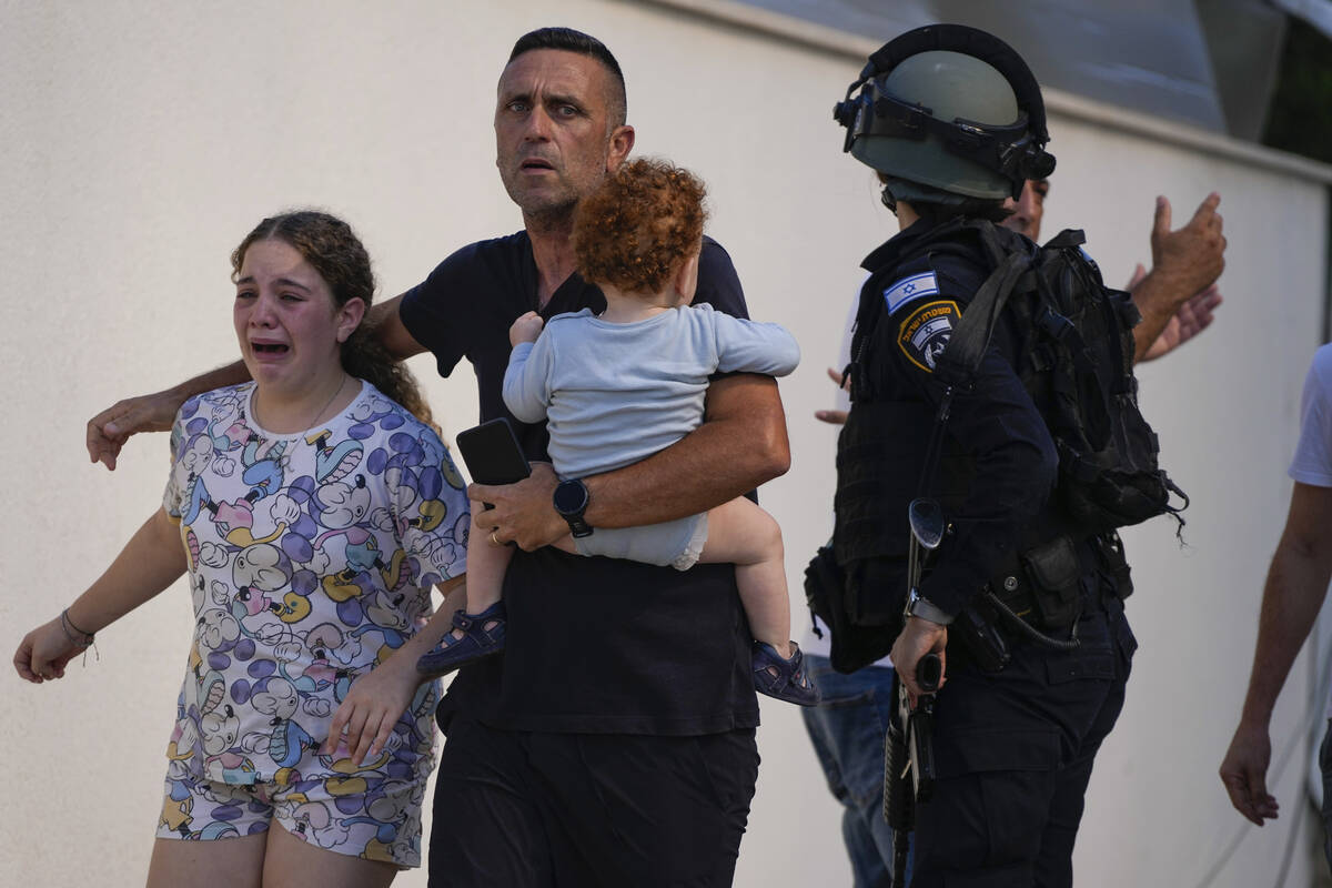 Israeli police officers evacuate a family from a site hit by a rocket fired from the Gaza Strip ...