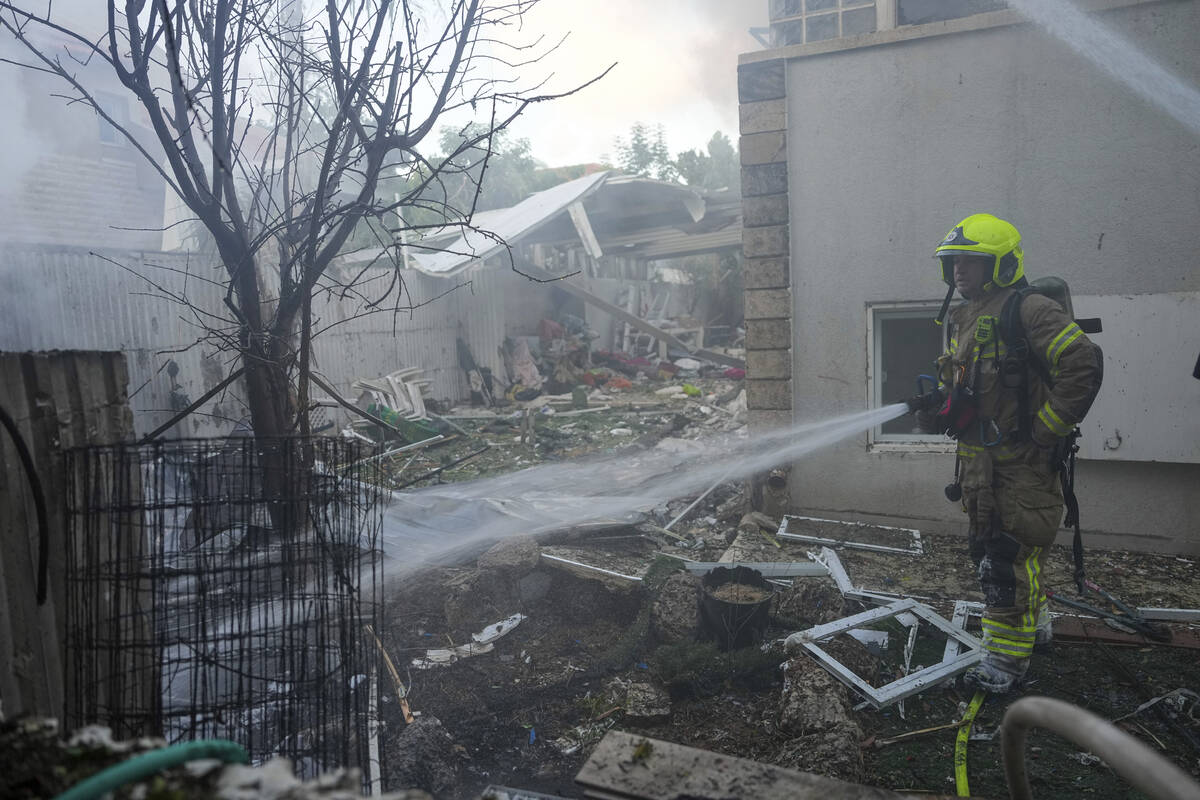 Israeli firefighters extinguish fire after a rocket fired from the Gaza Strip hit a house in As ...