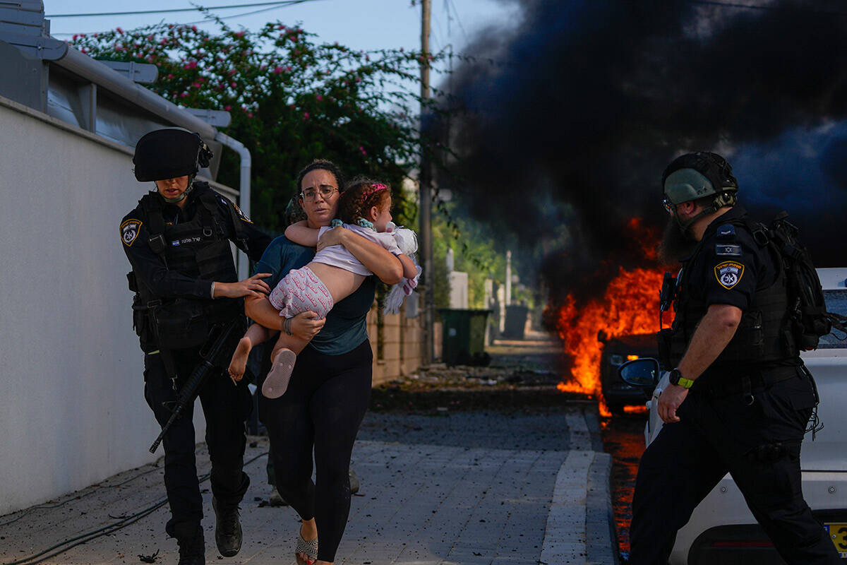 Police officers evacuate a woman and a child from a site hit by a rocket fired from the Gaza St ...