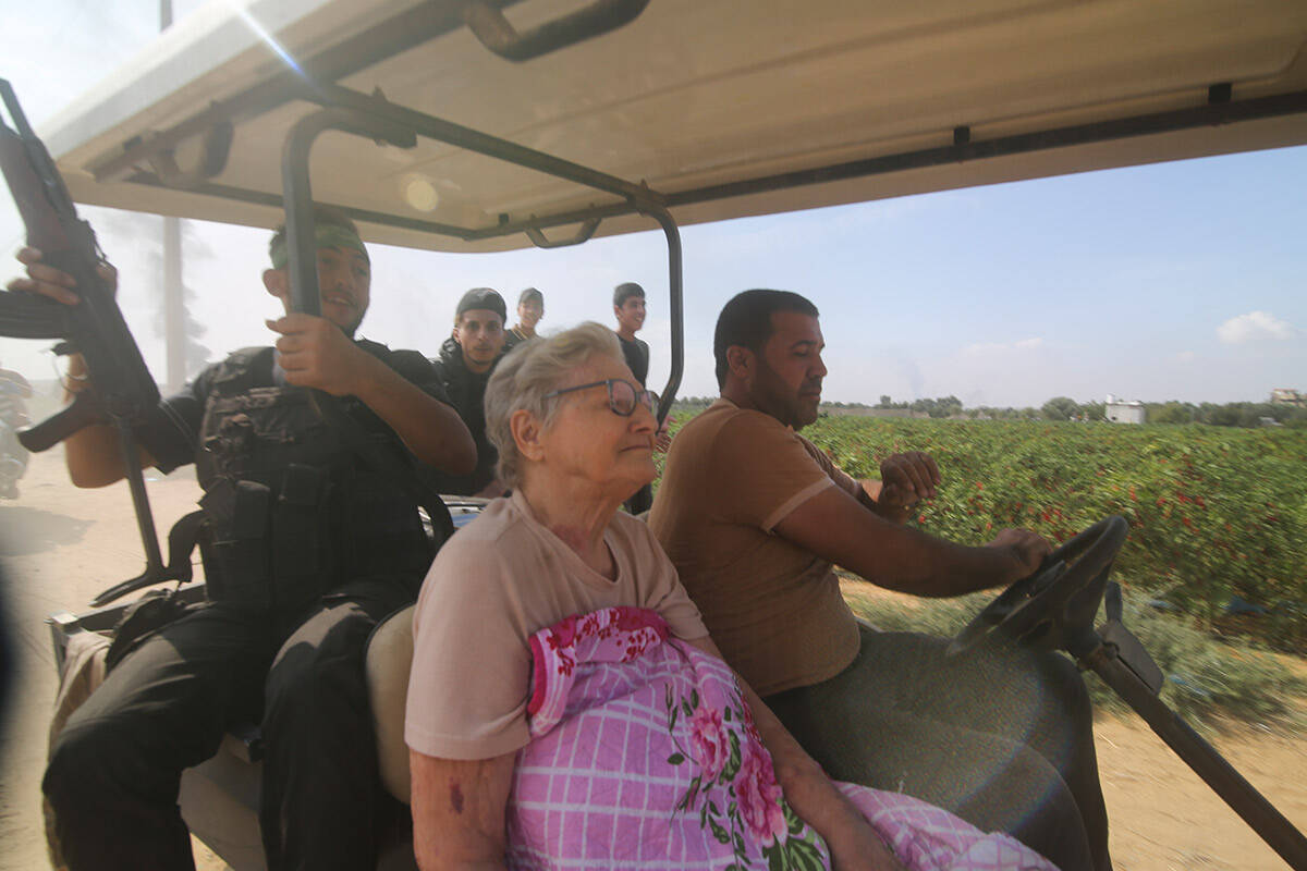 Palestinians transport a captured Israeli civilian, center, from Kibbutz Kfar Azza into the Gaz ...