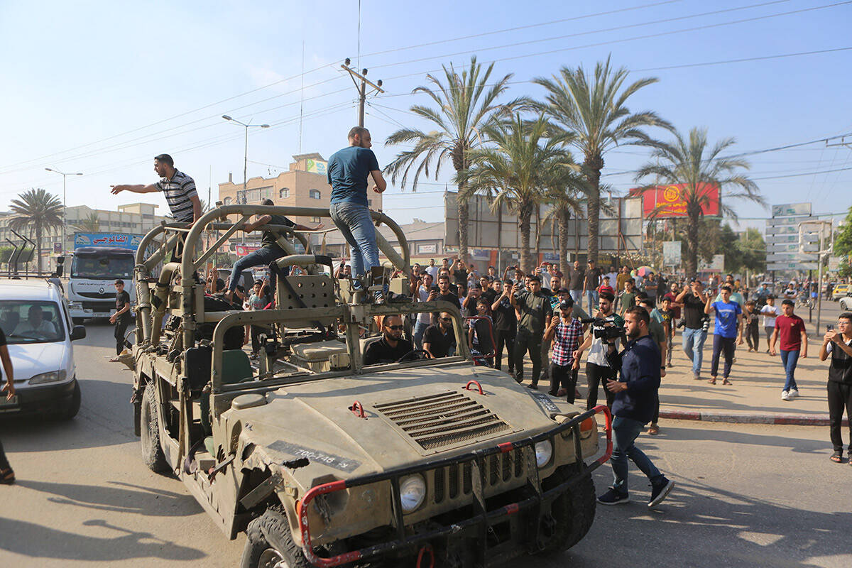 Palestinians ride on an Israeli military vehicle taken by an army base overrun by Hamas militan ...