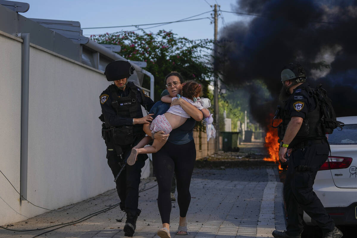 Israeli police officers evacuate a woman and a child from a site hit by a rocket fired from the ...