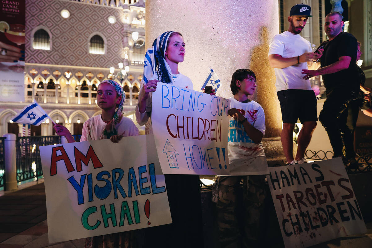 Supporters hold up signs during a pro-Israel rally outside the Venetian on Sunday, Oct. 8, 2023 ...