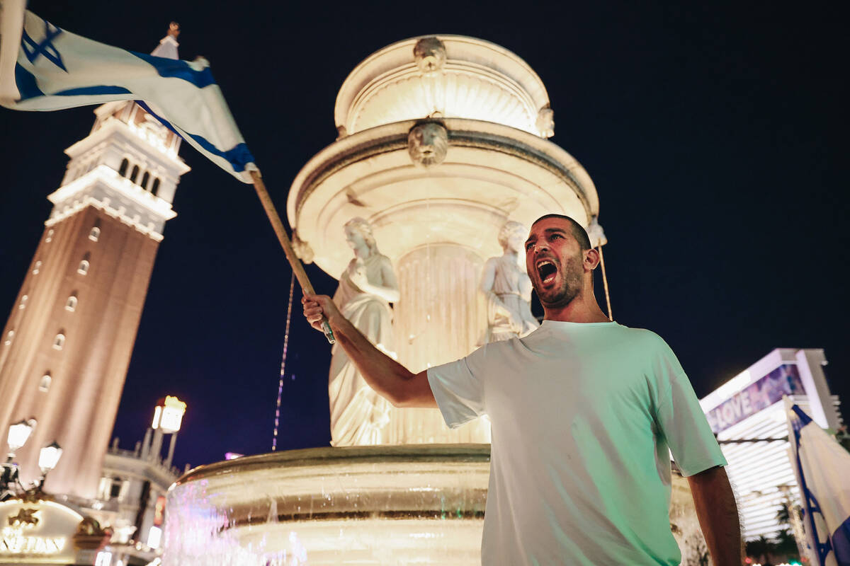 A man holds up an Israeli flag during a pro-Israel rally outside the Venetian on Sunday, Oct. 8 ...